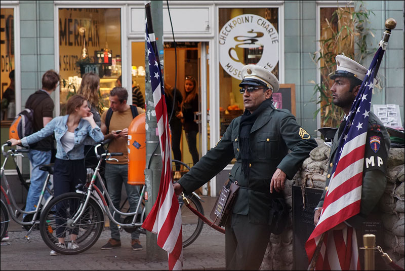 actors dressed as American soldiers wait to pose for tourist photos outside Checkpoint Charlie