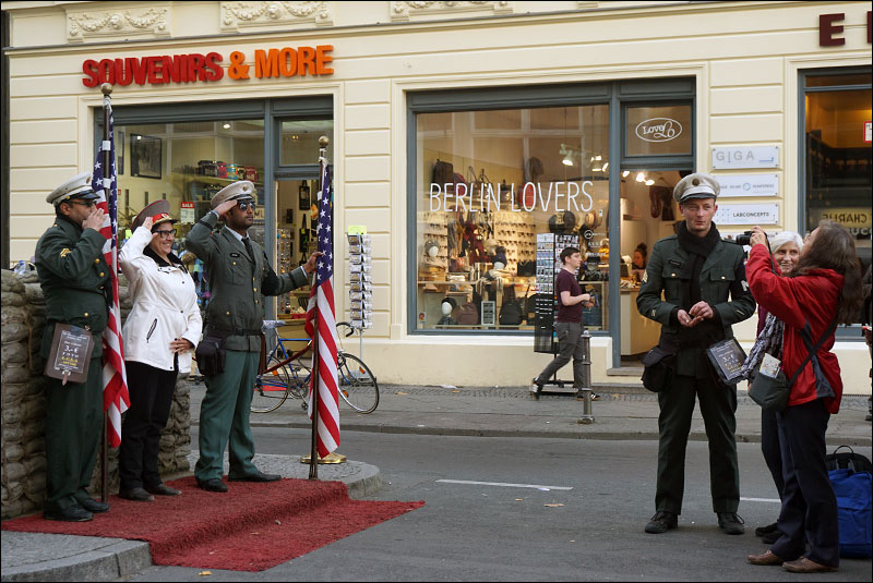 tourists pose with actors dressed as American soldiers at Checkpoint Charlie